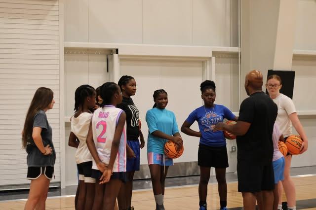 Players and coaches gathered with basketballs during an indoor practice.